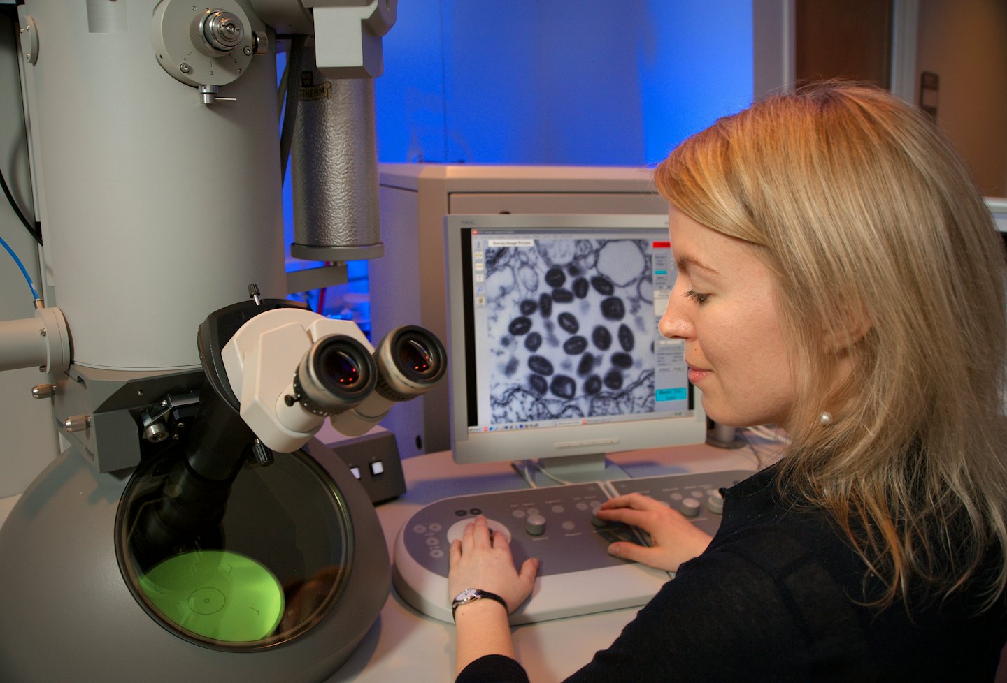 Scientist operating an electron microscope in a lab.